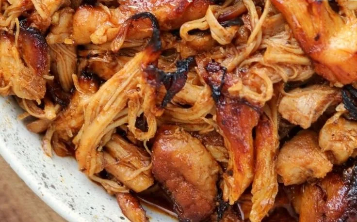 Delicious Instant Pot BBQ Pulled Chicken served in a bowl with sauce and herbs