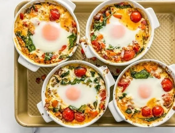 Baked feta eggs with tomatoes and spinach served in a dish