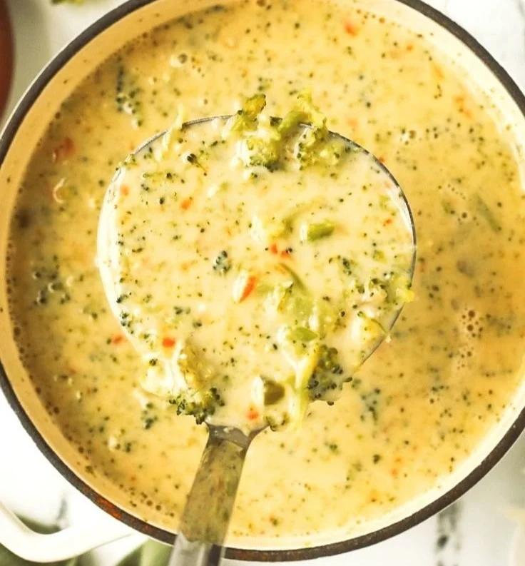 Bowl of creamy broccoli cheddar soup garnished with fresh broccoli florets