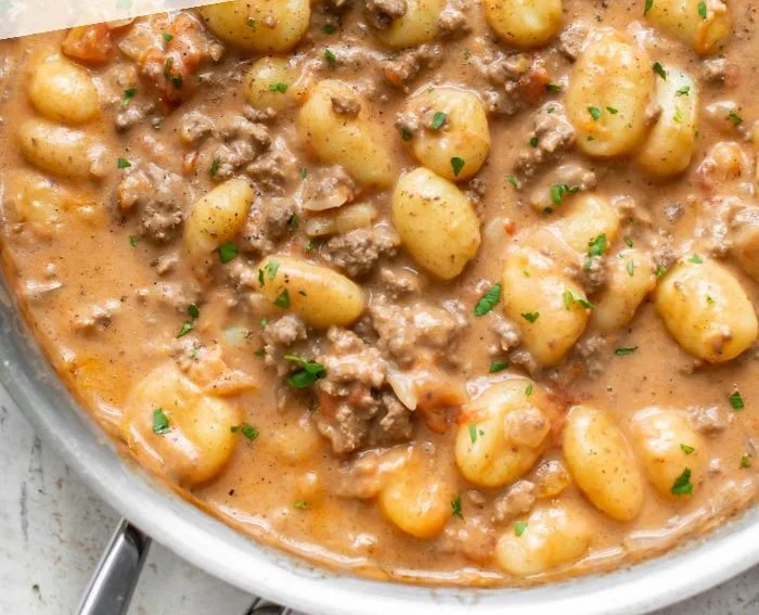 Creamy ground beef gnocchi dish garnished with parsley on a plate