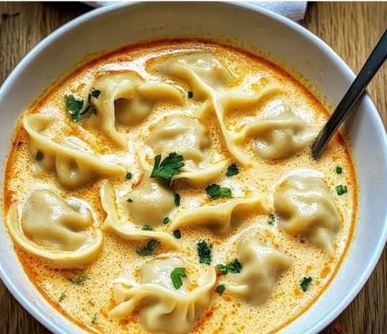 Creamy Thai dumpling soup in a bowl with fresh herbs and spices.