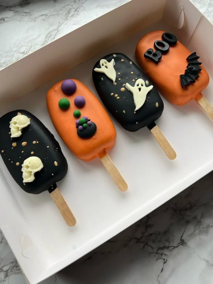 Colorful Halloween cakesicles decorated with spooky designs and festive colors.