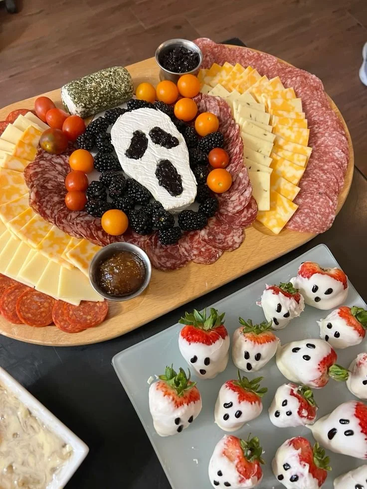 A spooky Halloween charcuterie board with themed snacks and decorations.