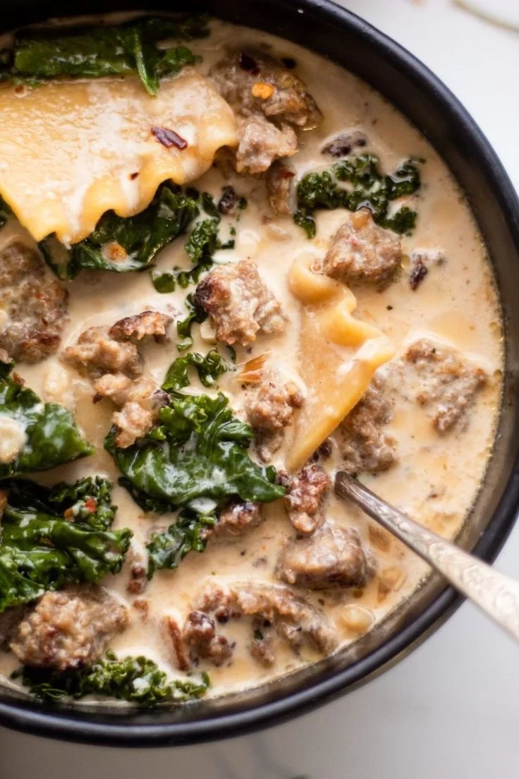 Creamy white lasagna soup in a bowl garnished with herbs.