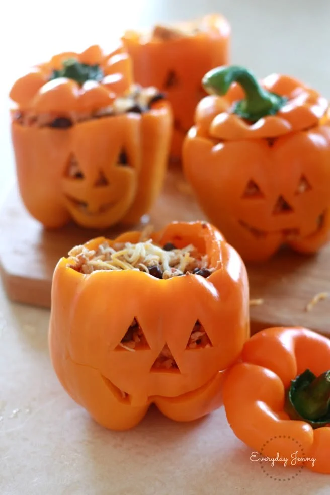 Halloween-style shredded chicken and rice stuffed peppers on a table.